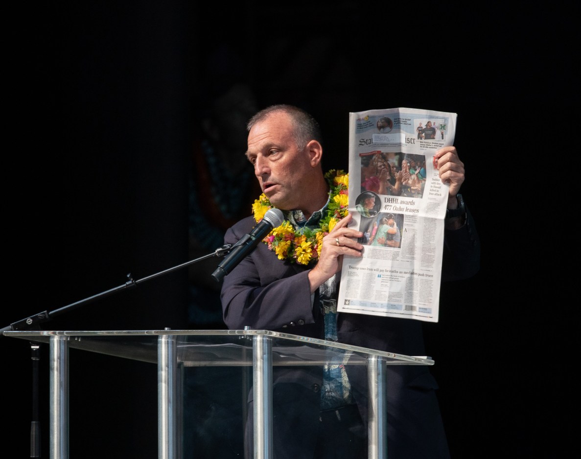 Gov. Green holds up a newspaper showing DHHL awarding 477 Oʻahu leases during remarks at the 2026 Native Hawaiʻian Convention at Blaisdell Center July 21, 2026. (Craig Fujii/Civil Beat/2026)