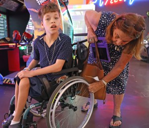 Linda Eblacas adjusts the wheel of her great-grandson Cylas Eblacas' wheelchair at Tilt arcade inside Prince Kūhiō Plaza in Hilo. The wheelchair replaced an earlier one after its frame was damaged. Photo by Tim Wright / newsphotoshawaii.com