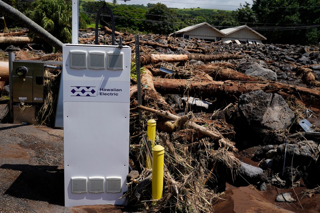 A HECO electric-vehicle fast charger appears undamaged below rubble and debris washed down from Nāʻālehu Cemetery Tuesday, Aug. 18, 2026, on Hawaiʻi Island. Hurricane Lala made a close pass to the South Point of the Big Island Saturday. (Kevin Fujii/Civil Beat/2026)