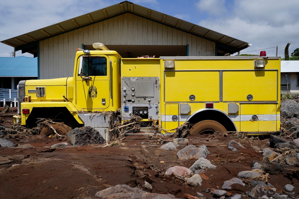 A Hawaiʻi County Fire Department vehicle lies buried in mud and debris as Nāʻālehu continues to recover Tuesday, Aug. 18, 2026, on Hawaiʻi Island. Hurricane Lala made a close pass to the South Point of the Big Island Saturday. (Kevin Fujii/Civil Beat/2026)