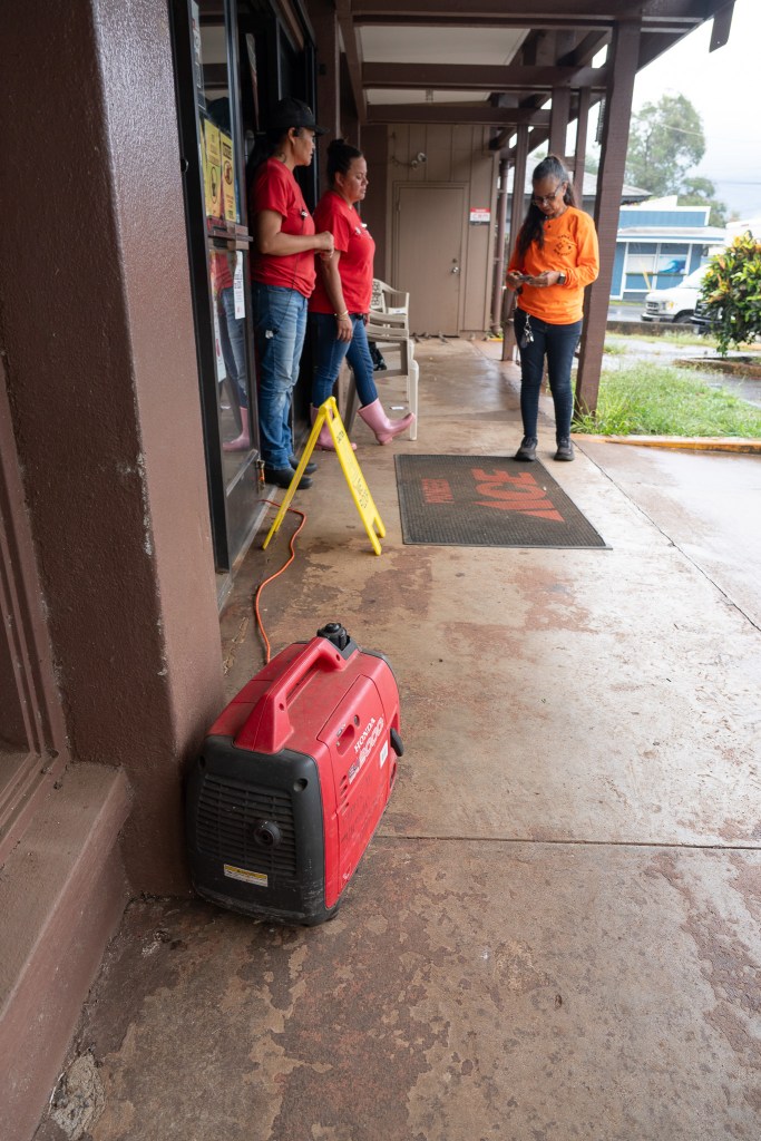 Ua Viernes, left, Malia Woods, center, and Margarita Emilyon wait for customers at their hardware store in Haleʻiwa after Lala passed south of Oʻahu August 16, 2026. They used a generator for some power. (Craig Fujii/Civil Beat/2026)