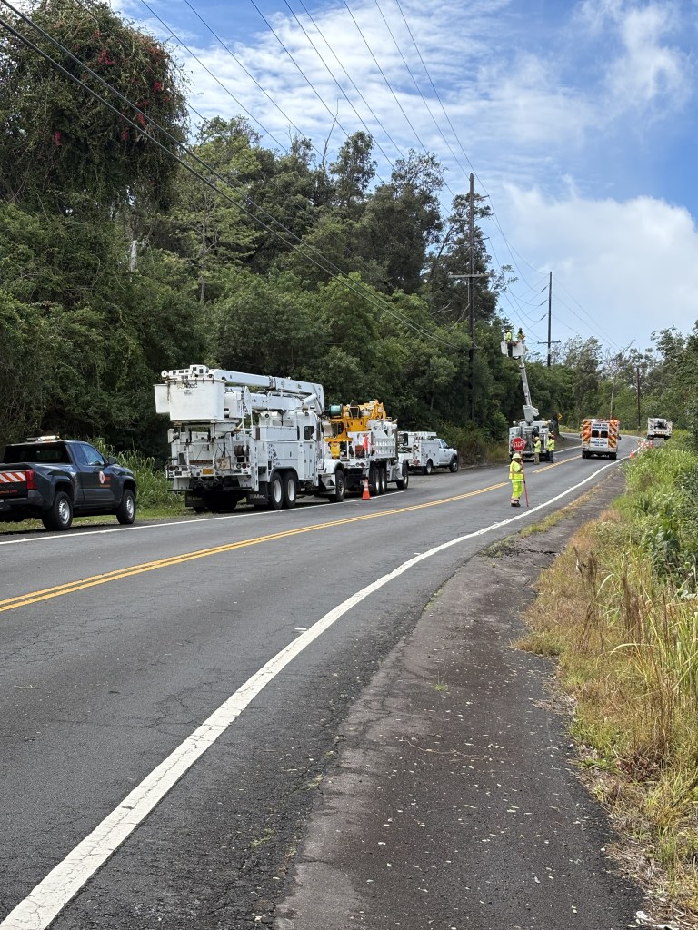An ambulance passes by technicians working to repair electrical lines in South Kona. (Twilight Greenaway/Civil Beat 2026)