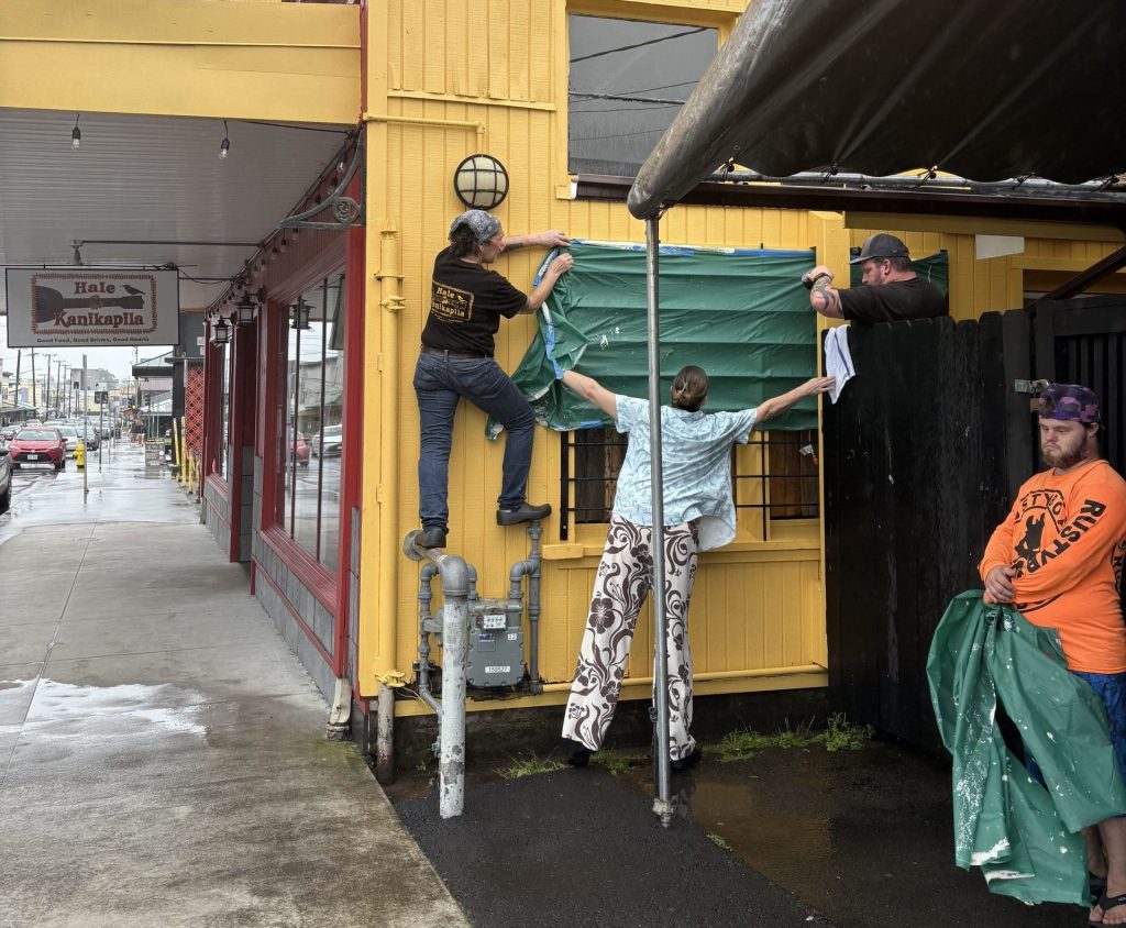 Workers tarp windows in downtown Hilo ahead of Lala.