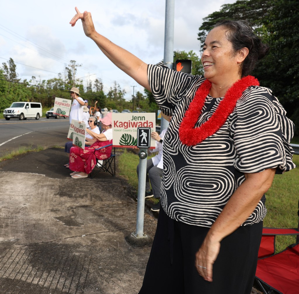 Hawaiʻi County Council District 2 Councilwoman Jenn Kagiwada waves to passing motorists in Hilo late Thursday afternoon during her final campaign sign-waving event before the Aug. 8 primary election. (Tim Wright/Civil Beat/2026)