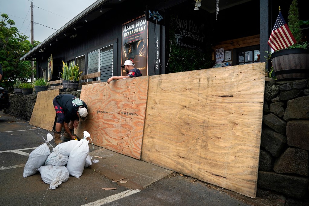 Hana Hou Restaurant managers Greg Febel, left, and Mark Umayam set plywood in front of the restaurant’s front door as Hawaiʻi Island prepares for Tropical Storm Nolo Thursday, Sept. 24, 2026, in Nāʻālehu. (Kevin Fujii/Civil Beat/2026)