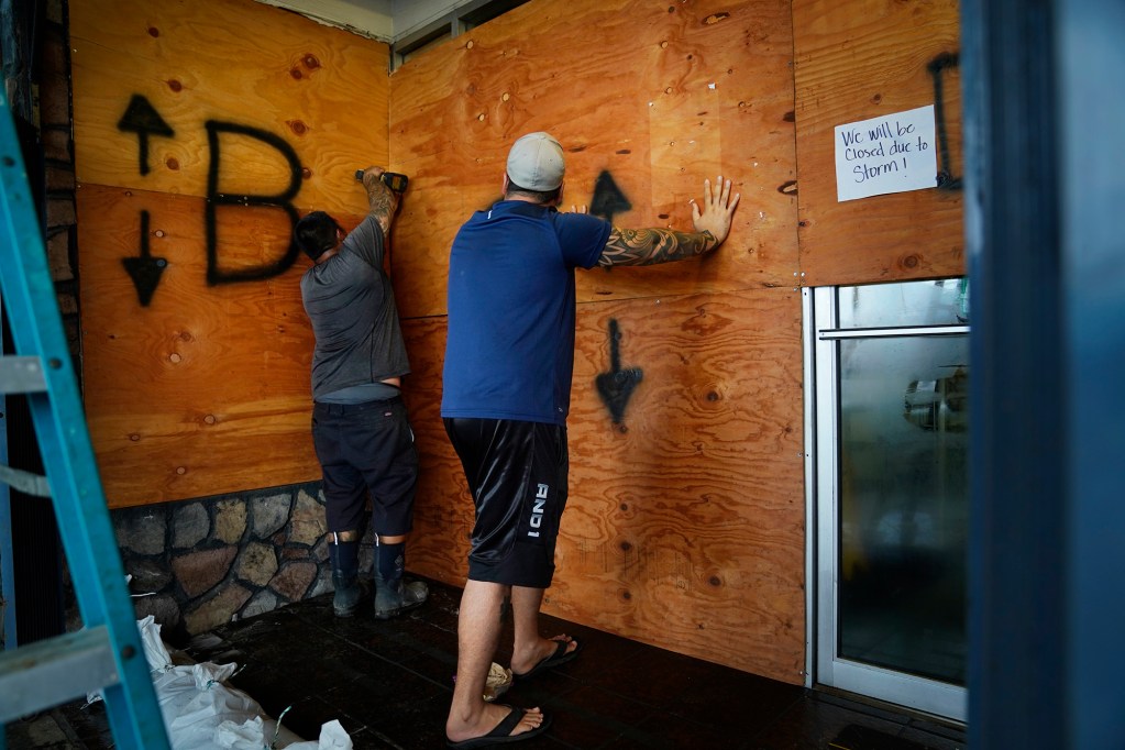 Ian Tanouye, from left, and Alex Rafizadeh  board up Bob’s Jewelers as Hawaiʻi Island prepares for Hurricane Nolo Friday, Sept. 25, 2026, in downtown Hilo. (Kevin Fujii/Civil Beat/2026)
