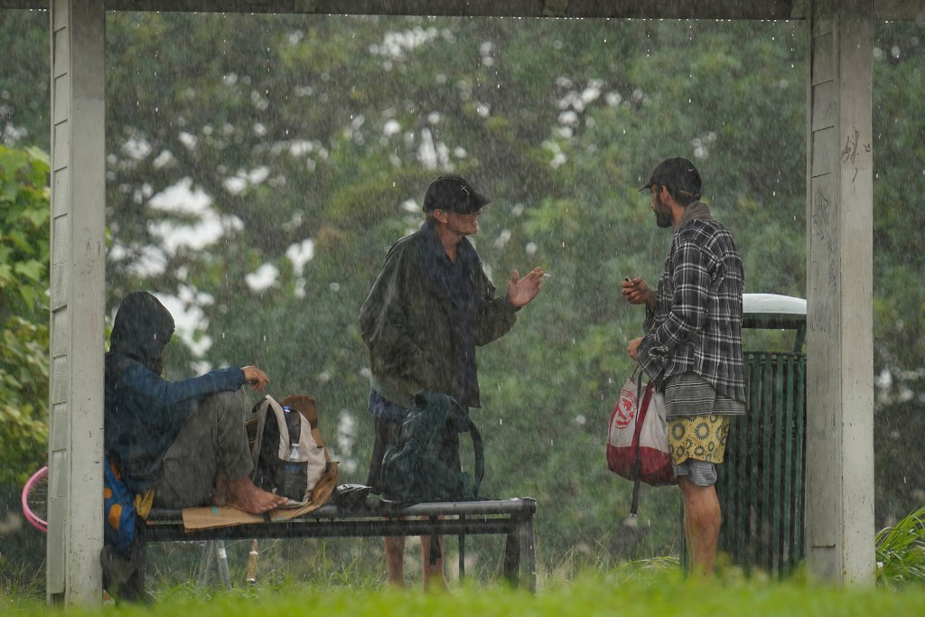 Homeless men get out of the rain under a bus stop as Hurricane Nolo’s outer bands hit Saturday, Sept. 26, 2026, in Volcano. (Kevin Fujii/Civil Beat/2026)