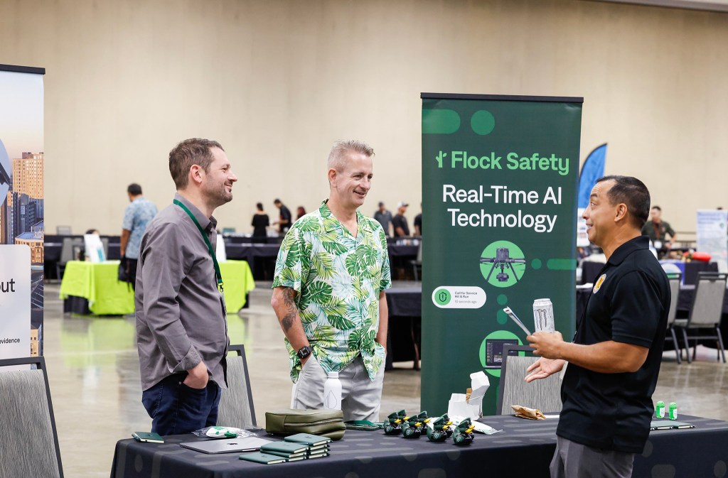 Flock Safety representatives Ben Shank, left, and Louis Wershaw talk with DLE chief special investigator Mike Lambert, right, during the Dept. of Law Enforcement’s Public Safety Expo, Saturday, Sept. 26, 2026, at the Hawaiʻi Convention Center in Honolulu. (Jamm Aquino/Civil Beat/2026)