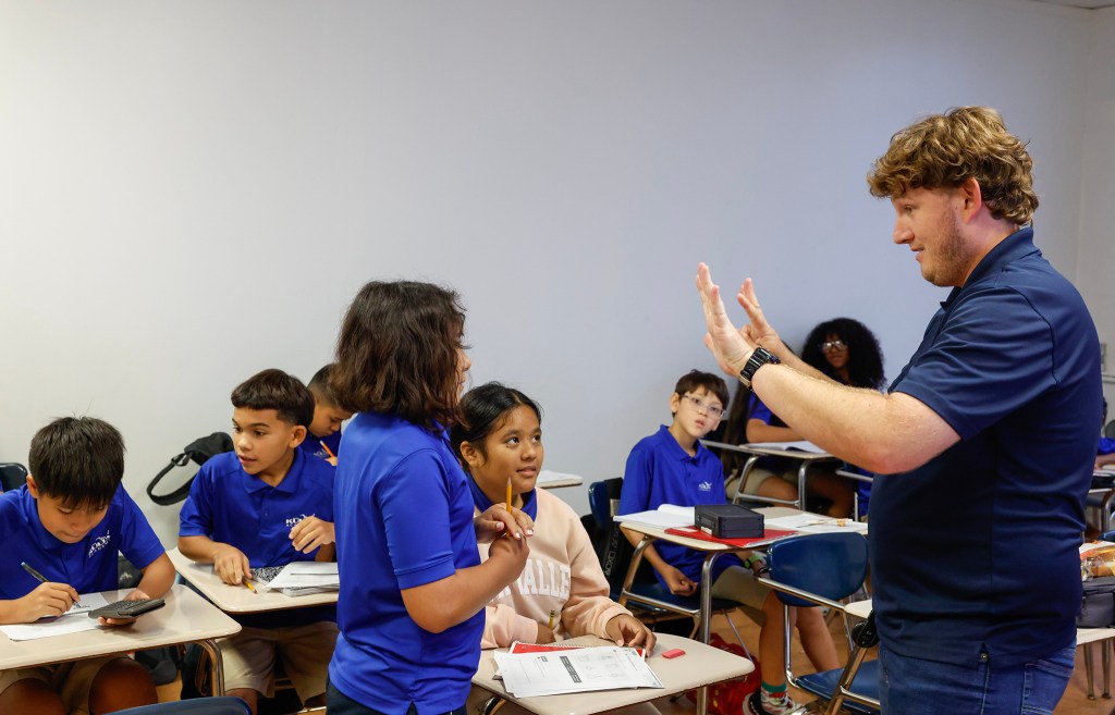 Sixth-grade math teacher Byron Bass, right, assists students Hope Singeuo, middle, and Angelica Meikei,front, with a math problem at Kūlia Academy, Wednesday, Sept. 30, 2026, in Kalihi. Kūlia Academy’s middle school math achievement has had unprecedented improvement, and had the highest middle school math scores in the state last year. (Jamm Aquino/Civil Beat/2026)