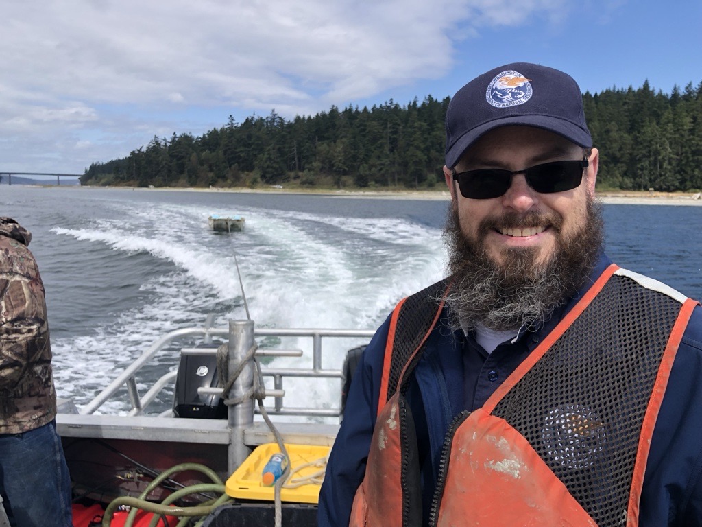 Man in blue cap and black sunglasses on a speedboat.