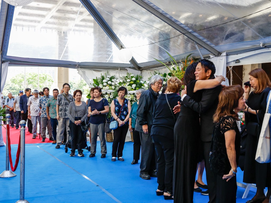 People wait to pay respects to the Ariyoshi family during a formal procession for the casket of former Hawaiʻi Governor George Ariyoshi, Friday, Sept. 18, 2026, in Honolulu. Ariyoshi’s casket will lie in state at the State Capitol rotunda through Saturday.  (Jamm Aquino/Civil Beat/2026)