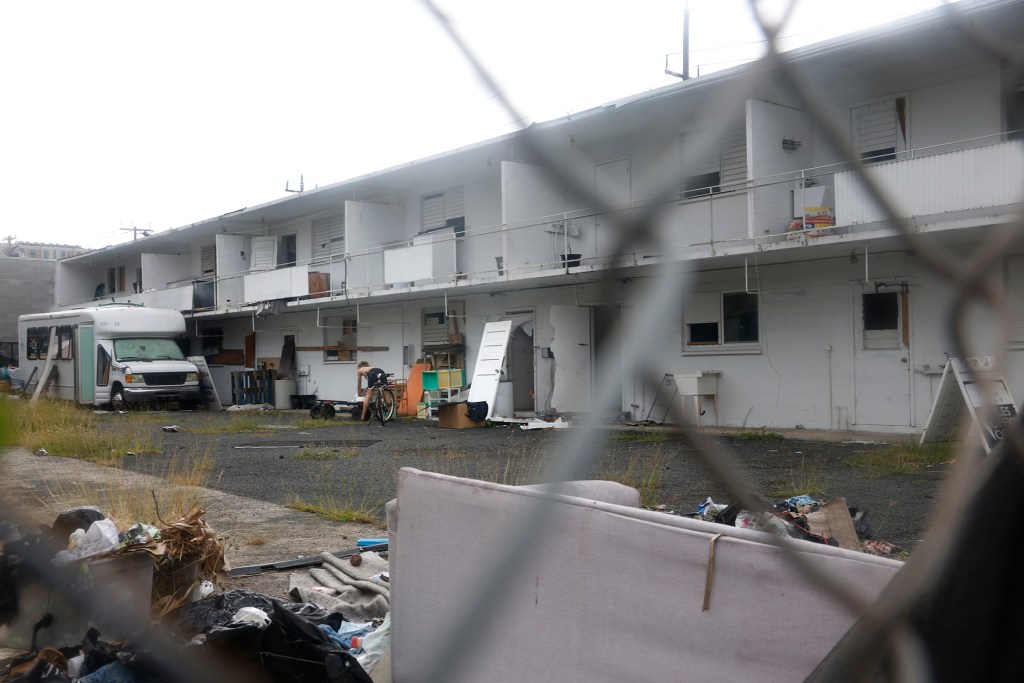 A woman walks out from 929 Pumehana Street to use a wash basin Tuesday, Oct. 20, 2026, in Honolulu. A neighboring business alleges this building is a hotbed of squatters, illegal drugs and game rooms. (Kevin Fujii/Civil Beat/2026)