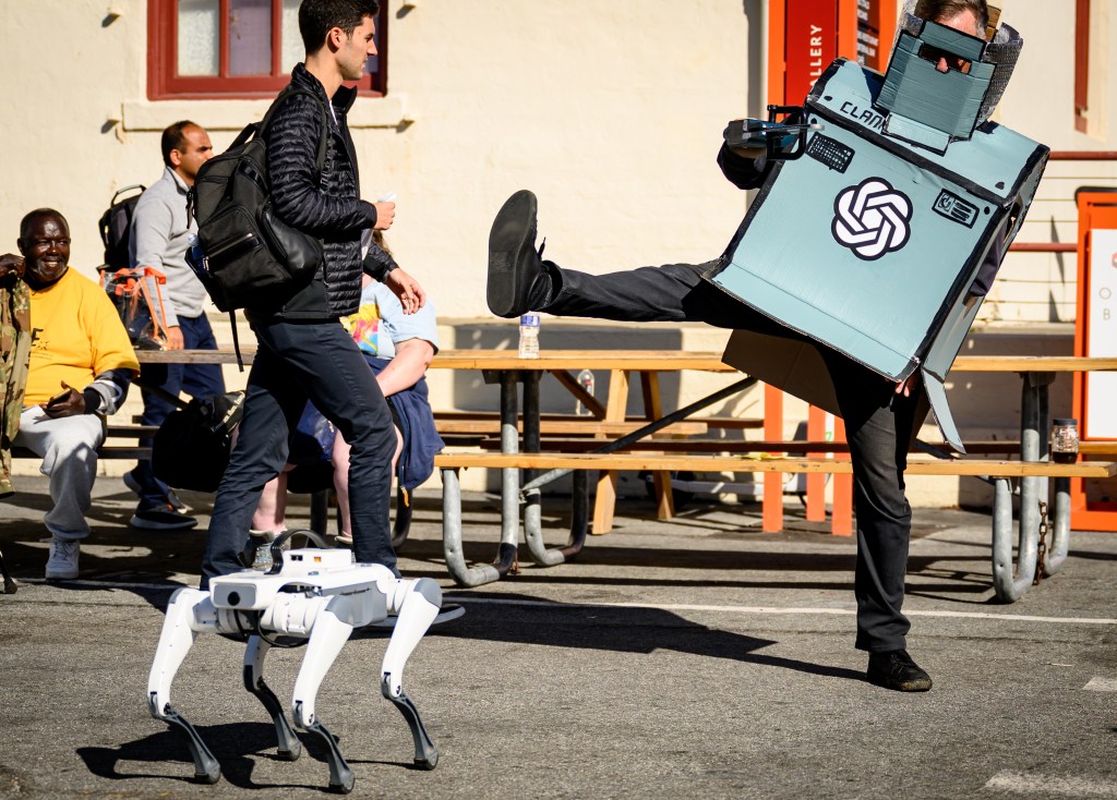 An AI protester raises their foot against a robot dog outside the OpenAI DevDay 2026 conference in San Francisco, on Tuesday, Sept. 29, 2026. (AP Photo/Josh Edelson)