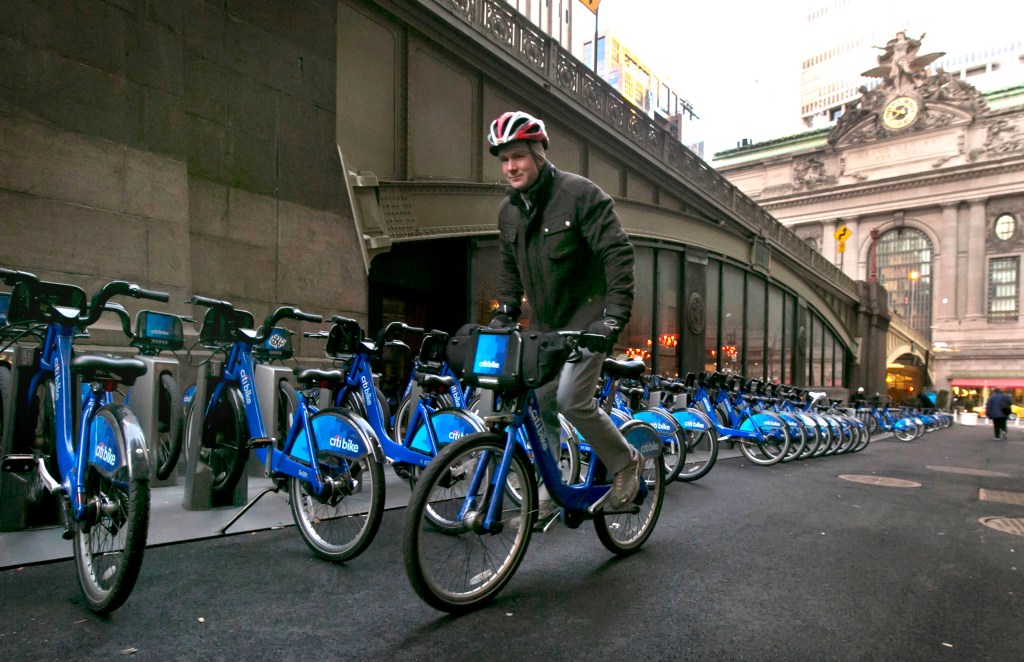 A Citbike cyclist picks up his ride near Grand Central Terminal, background right, in New York, Tuesday, Jan. 13, 2015. Now that it has moved from laid-back Portland, Oregon, to amped-up New York, the company that runs bike-sharing programs in New York, Chicago and other major cities is changing its name from Alta Bicycle Share to Motivate. (AP Photo/Richard Drew)