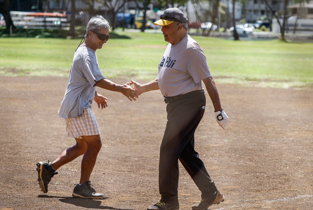 Francis Lum, right, shakes hands with team mate Vince Kanemoto during a softball game, Monday, Oct. 5, 2026, in Mōʻiliʻili. Lum plays three times a week along with batting practice on Tuesdays.  (Jamm Aquino/Civil Beat/2026)