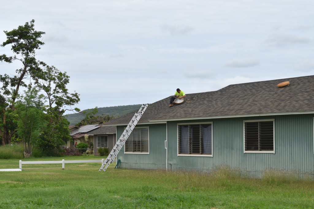 A maintenance worker fixes a metal vent cap on the roof of Joseph Naka‘ahiki's unit at Kekaha Ha‘aheo. The cap was displaced during Hurricane Lowell and caused Naka‘ahiki's ceiling to leak.